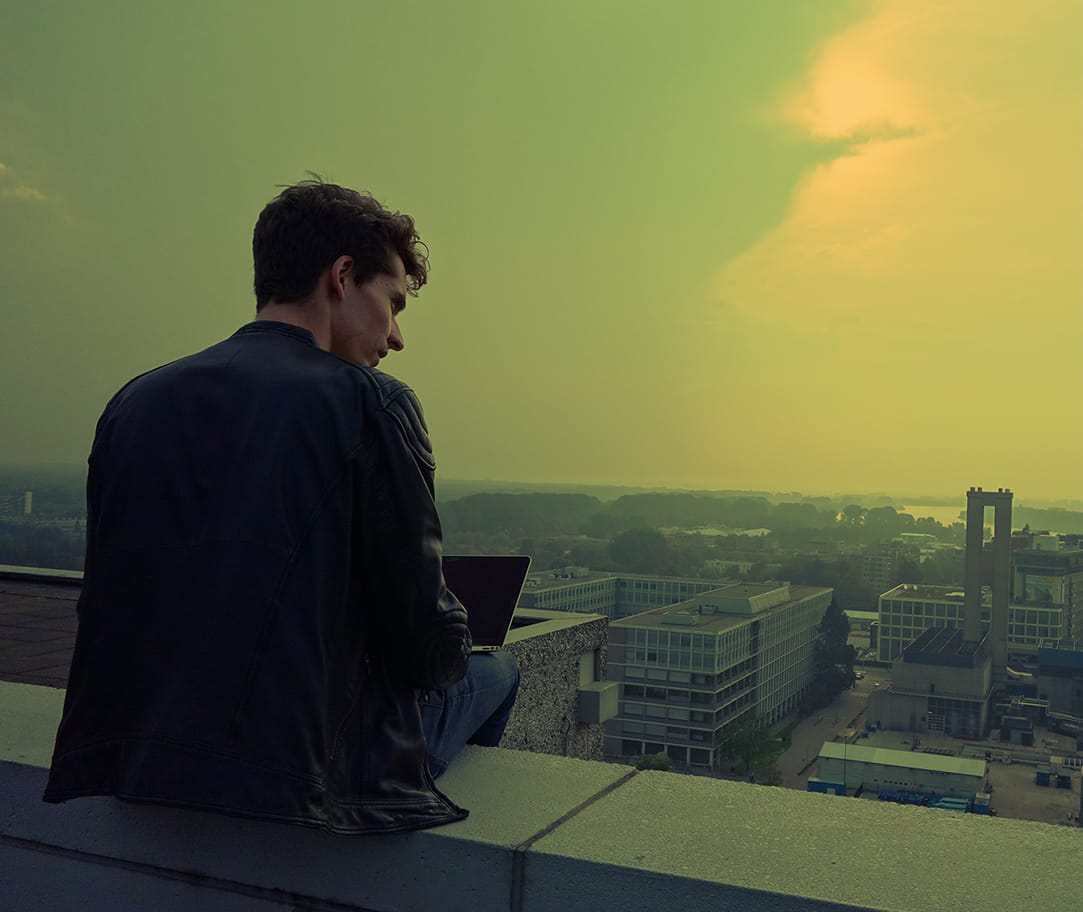 Gerwin with his laptop on a rooftop, looking out over the city